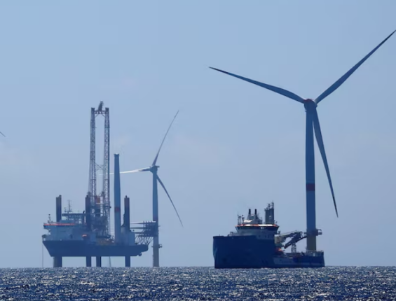 an image of a wind turbine in the ocean surrounded by a construction site and a large ship